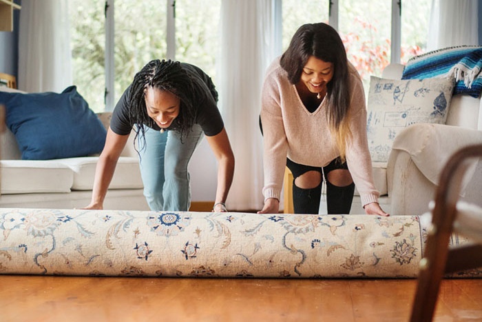 Mom and daughter rolling out new rug in living room